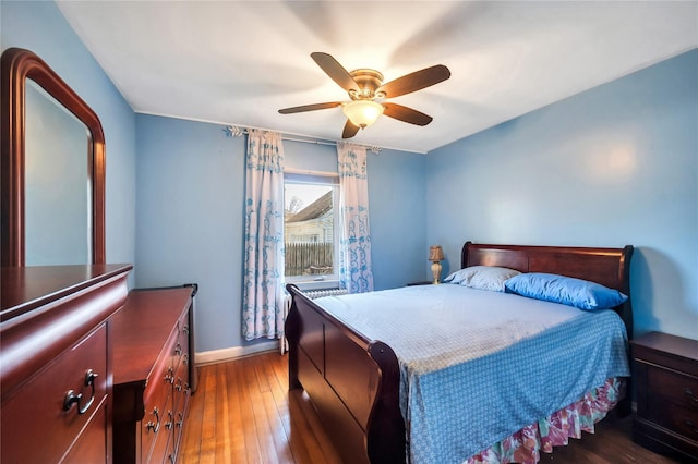 bedroom featuring baseboards, hardwood / wood-style flooring, and a ceiling fan