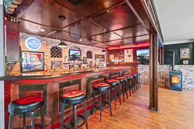 bar featuring visible vents, a wood stove, wood finished floors, brick wall, and a dry bar