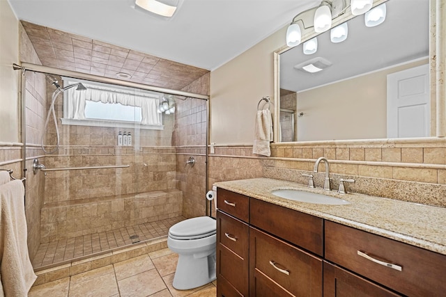 full bath with vanity, toilet, tile walls, tile patterned floors, and a shower stall