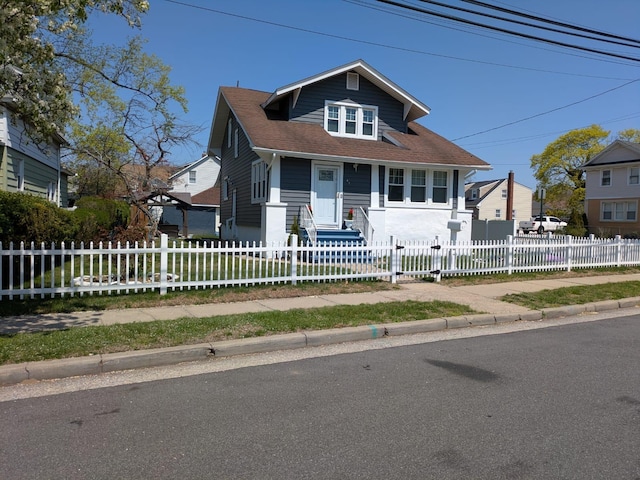 bungalow with a shingled roof and a fenced front yard