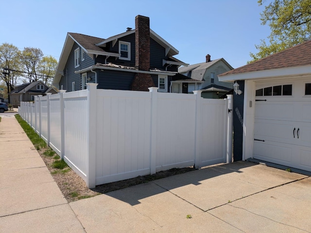 view of property exterior featuring fence, a chimney, a gate, and a garage