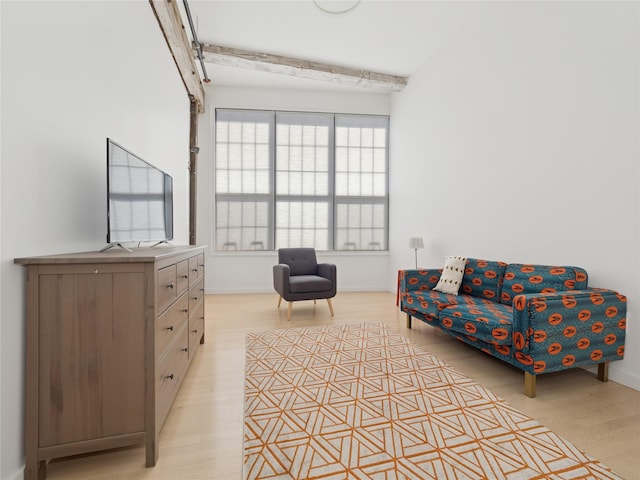 sitting room featuring baseboards, beam ceiling, and light wood-style floors