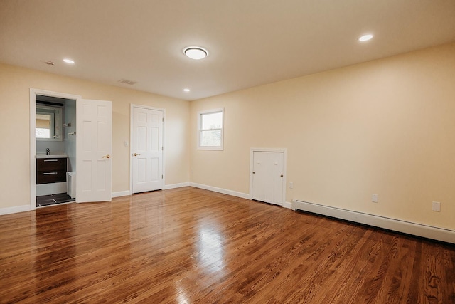 unfurnished bedroom featuring wood finished floors, visible vents, baseboard heating, and baseboards