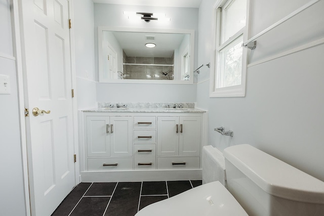 full bathroom featuring toilet, tiled shower, tile patterned flooring, and a sink