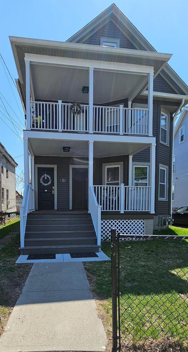 view of front of house featuring covered porch, a balcony, and a front yard