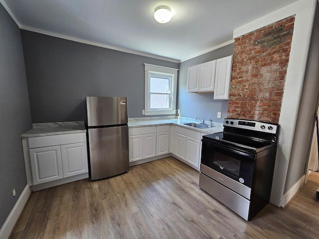 kitchen with white cabinets, a sink, light wood-style floors, stainless steel appliances, and ornamental molding
