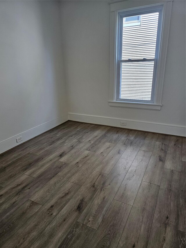 spare room with dark wood finished floors and baseboards