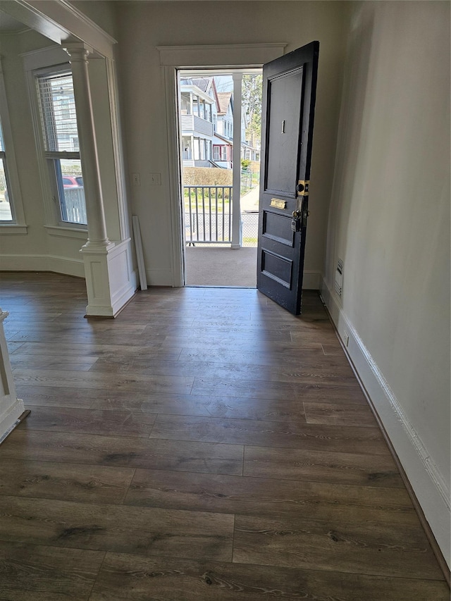 doorway to outside featuring dark wood-style floors, decorative columns, and baseboards