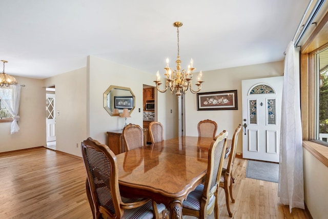 dining space with an inviting chandelier, baseboards, and light wood-type flooring