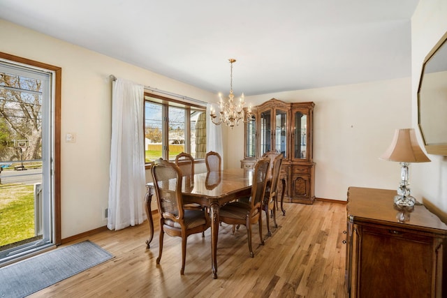 dining area featuring a chandelier, baseboards, and light wood finished floors