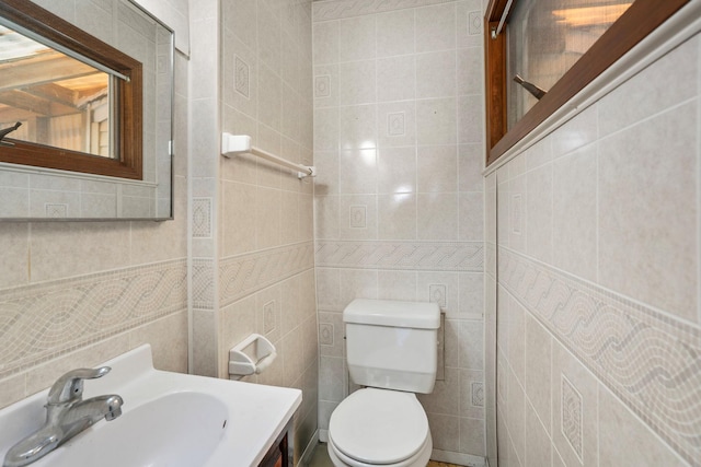 bathroom with tile walls, toilet, and a sink