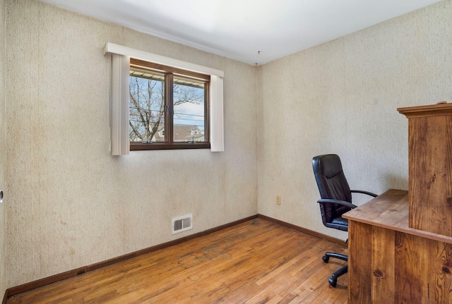 unfurnished office featuring visible vents, hardwood / wood-style floors, and baseboards