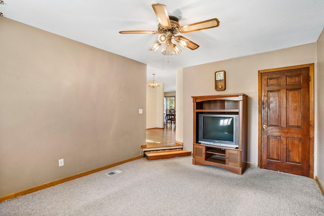carpeted living area with visible vents, baseboards, and ceiling fan with notable chandelier