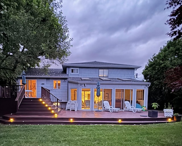 rear view of property featuring stairway, a yard, a shingled roof, and a wooden deck
