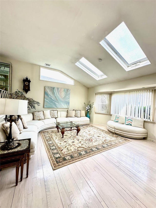 living room featuring lofted ceiling with skylight, visible vents, and hardwood / wood-style floors