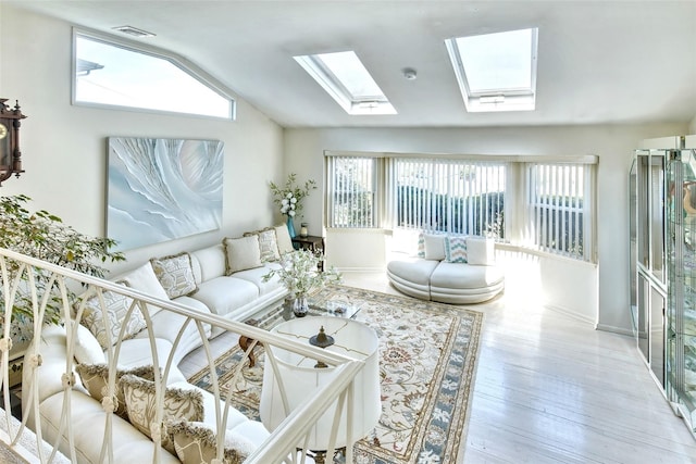 living room featuring baseboards, visible vents, wood finished floors, and lofted ceiling with skylight
