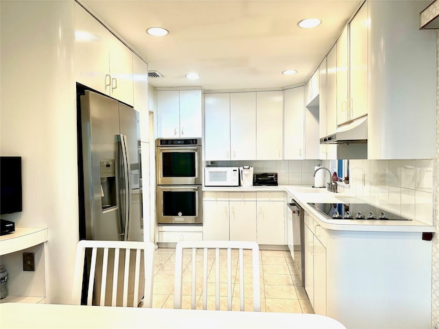 kitchen with under cabinet range hood, appliances with stainless steel finishes, backsplash, a sink, and visible vents