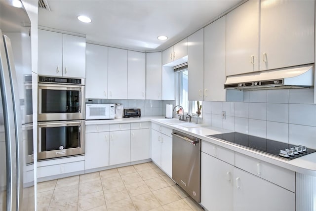 kitchen with a sink, stainless steel appliances, under cabinet range hood, tasteful backsplash, and light countertops