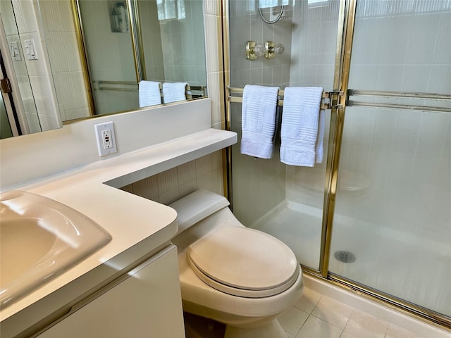 bathroom with a shower stall, toilet, tile walls, vanity, and tile patterned flooring