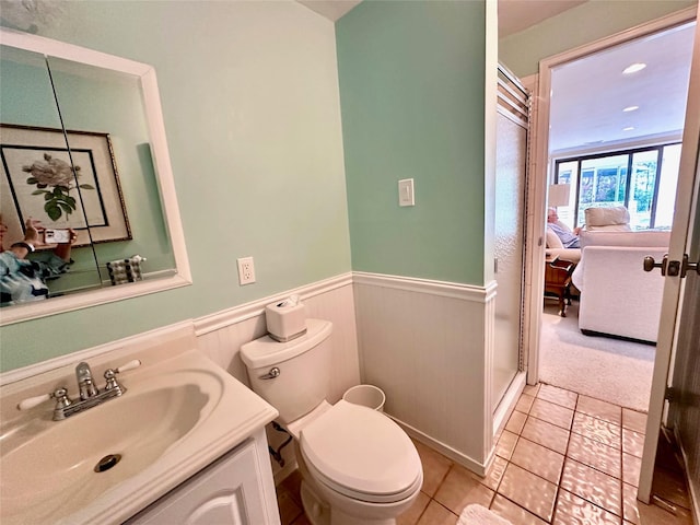 full bathroom with a wainscoted wall, a stall shower, toilet, tile patterned floors, and vanity