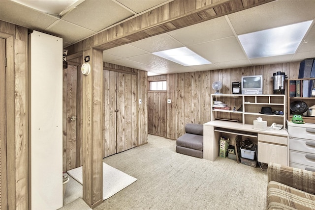 interior space with a drop ceiling and wood walls