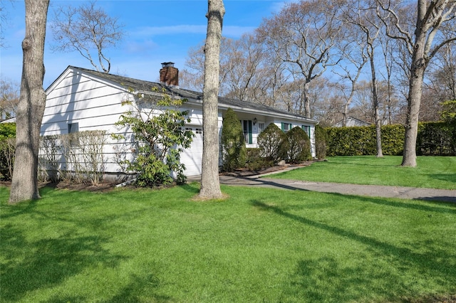 view of front of house featuring a chimney, a front yard, and an attached garage