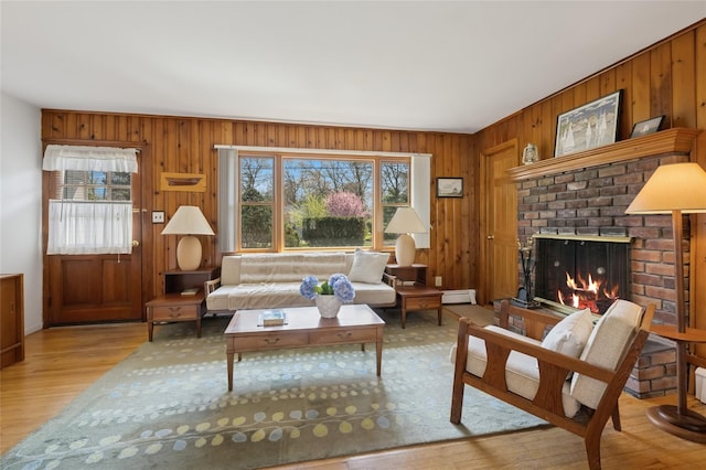 living area with a brick fireplace, baseboard heating, wood walls, and wood finished floors
