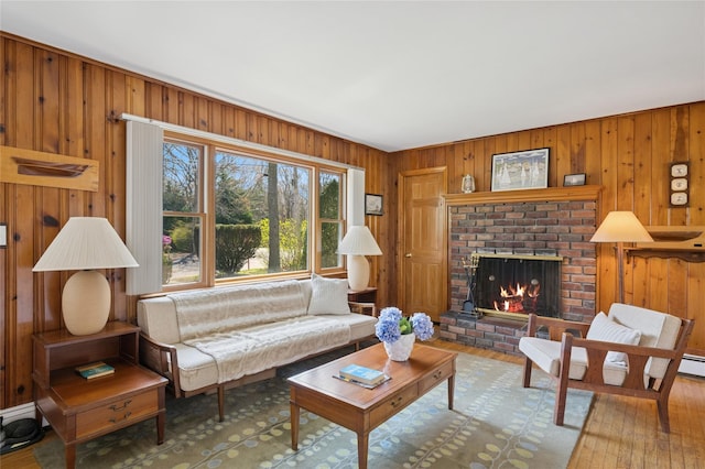 living room featuring wooden walls, wood-type flooring, and a brick fireplace