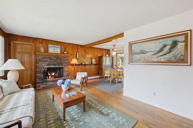 living room with wooden walls, baseboards, wood finished floors, and a fireplace