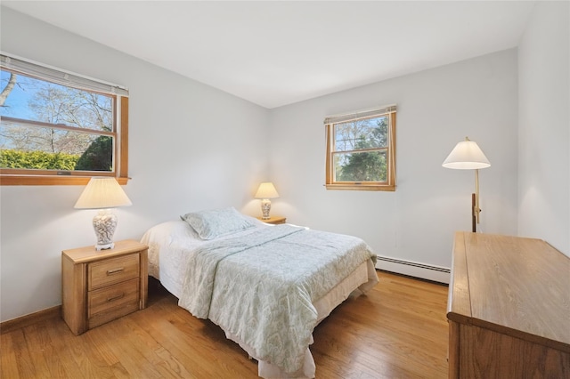 bedroom with baseboards, light wood-type flooring, and a baseboard radiator
