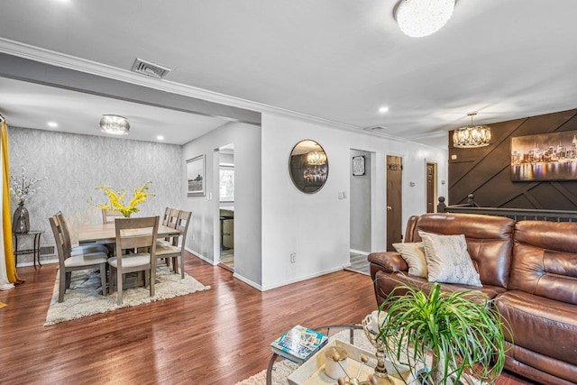 living room featuring wood finished floors, a chandelier, baseboards, visible vents, and crown molding