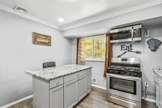 kitchen with appliances with stainless steel finishes, visible vents, ornamental molding, and baseboards