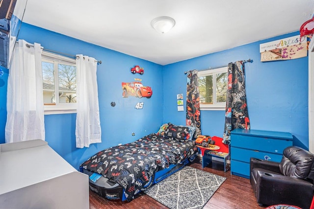bedroom with multiple windows and wood finished floors