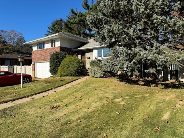 tri-level home featuring a garage, brick siding, fence, and a front lawn
