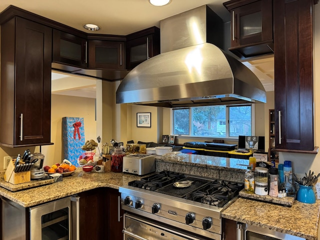 kitchen with dark brown cabinetry, island exhaust hood, light stone countertops, stovetop with downdraft, and wine cooler