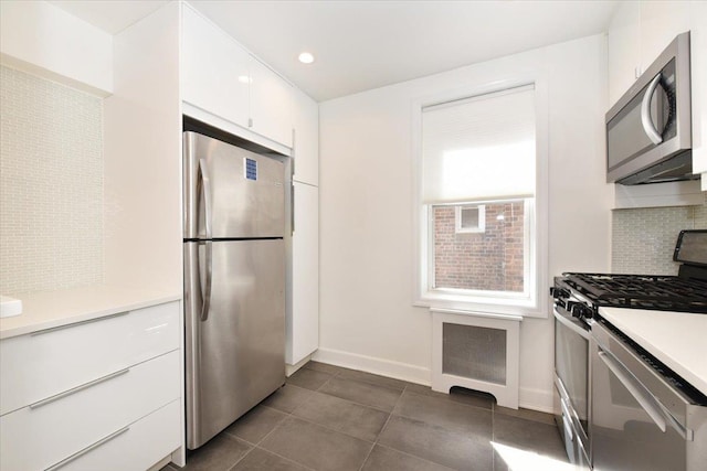 36 Barstow Unit 2-B, Great Neck, NY 11021 - kitchen with decorative backsplash, appliances with stainless steel finishes, light countertops, baseboards, and white cabinets