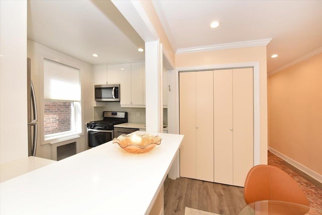 36 Barstow Unit 2-B, Great Neck, NY 11021 - kitchen featuring recessed lighting, stainless steel appliances, light countertops, light wood finished floors, and crown molding