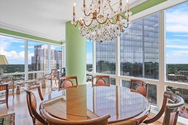 dining area featuring wood finished floors, a notable chandelier, a city view, and crown molding