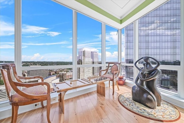 sunroom / solarium featuring a city view, floor to ceiling windows, hardwood / wood-style flooring, and ornamental molding