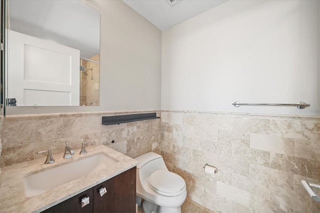 full bath featuring tile walls, a wainscoted wall, toilet, vanity, and a shower