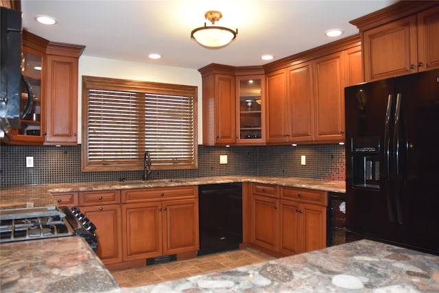 kitchen featuring brown cabinetry, a sink, black appliances, and tasteful backsplash