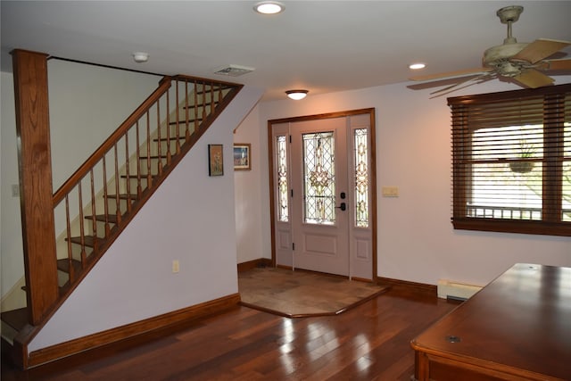 foyer entrance featuring wood finished floors, baseboards, stairway, a baseboard heating unit, and a ceiling fan