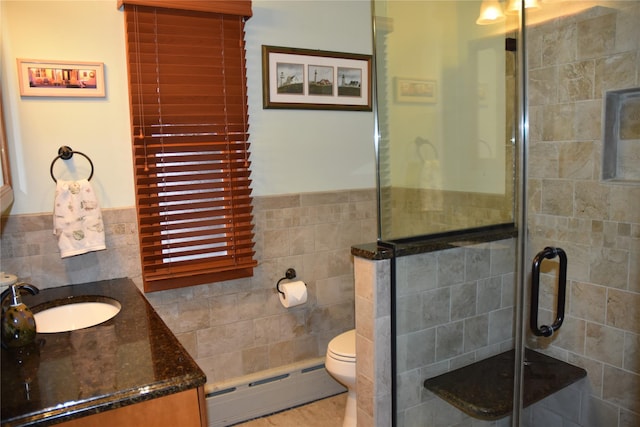 full bath with vanity, toilet, tile walls, a shower stall, and a baseboard heating unit