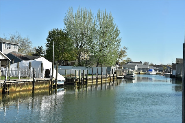 dock area featuring a water view, fence, and a residential view