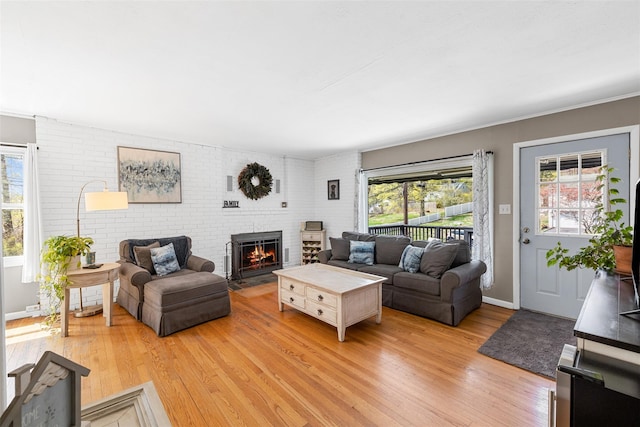 living area featuring baseboards, a wealth of natural light, light wood-style floors, and a fireplace