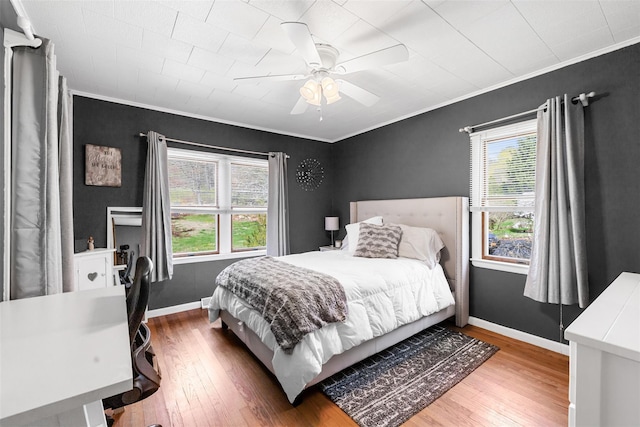 bedroom with wood-type flooring, crown molding, and multiple windows