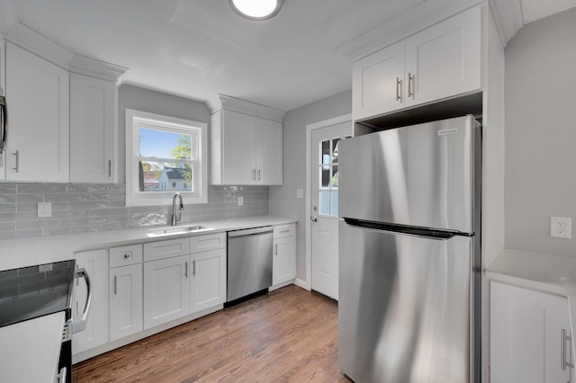 kitchen with tasteful backsplash, white cabinetry, stainless steel appliances, and a sink
