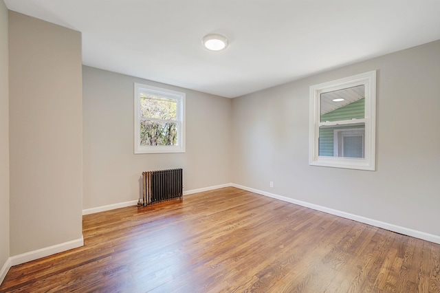 spare room with radiator heating unit, wood finished floors, and baseboards