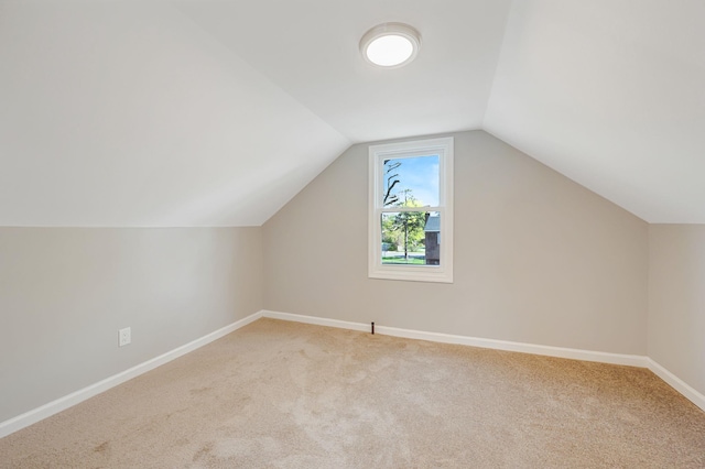 additional living space featuring baseboards, light carpet, and lofted ceiling