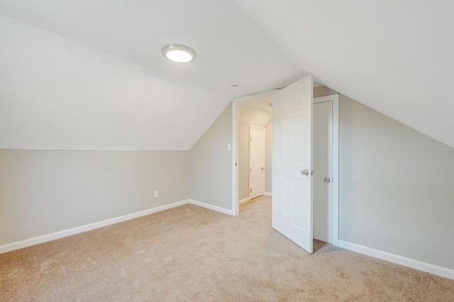 bonus room with baseboards, lofted ceiling, and light colored carpet